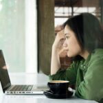 パソコンを前に頭をかかえている女性の画像
