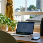 机の上にノートパソコンと観葉植物と瓶が置いてある画像