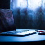暗い背景にノートパソコンが置かれている画像