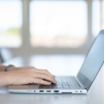 ノートパソコンでタイピングしている姿を横からとって画像