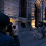 夕暮れの街で走る自転車を撮影するフォトグラファー