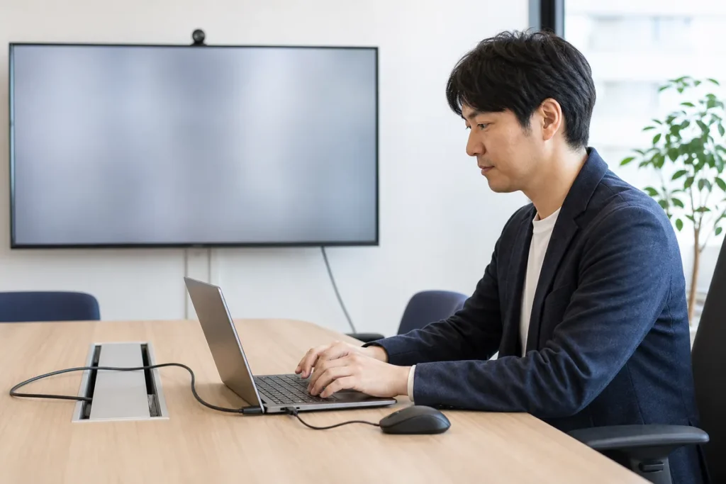 会議室でノートPCを外部機器につないで作業する様子