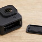 乾いた作業台に置いた無銘のアクションカメラと外したバッテリードア