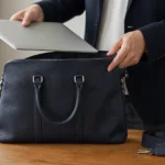 ビジネスバッグの横に置いたノートパソコンと別売ストラップ