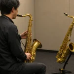 練習室で2本のテナーサックスを比較する演奏者