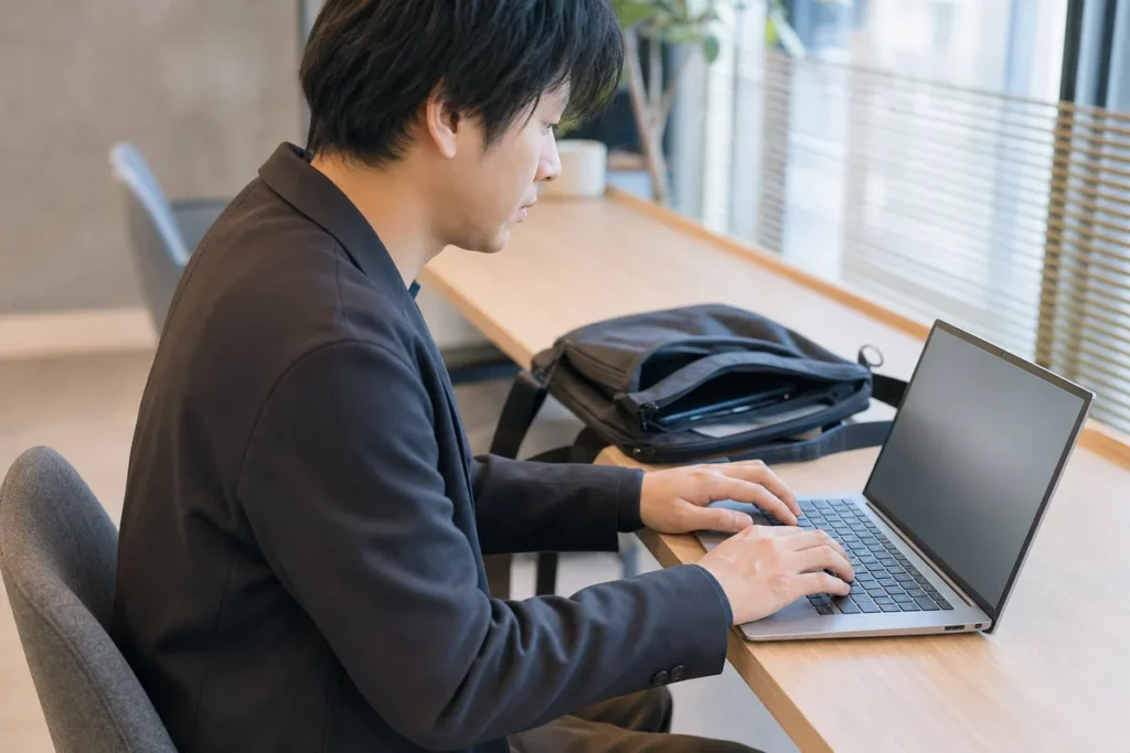 バッグをそばに置き持ち運んだノートPCで入力作業をする様子