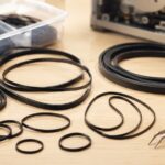 作業台に並べた複数サイズの黒いゴムベルトとピンセット