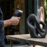 黒い立体物を手持ちスキャナーで読み取る屋外の作業者
