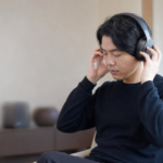 オーディオ試聴室で大型ヘッドホンの装着感を確かめる人物