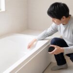 浴室で浴槽の内寸をメジャーで測る人物