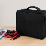 測定器用の黒い携帯ケースとテストリードを机上に並べたイメージ