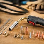 半自動溶接機のトーチと交換用ノズルやチップを作業台に並べたイメージ