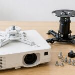 プロジェクターと天吊り金具、複数サイズの取付ネジが並んでいる様子