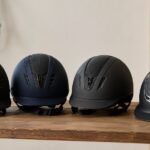 木製テーブルに複数の乗馬用ヘルメットを並べたイメージ