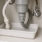 洗面台下の配管と白い水受けトレー