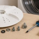 洗濯機のパルセーターと交換用ネジ、ドライバーを並べたイメージ