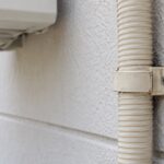 外壁のドレンホースを樹脂製サドルで固定している様子