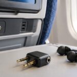 飛行機の座席テーブルに2ピン変換プラグと有線イヤホンを置いたイメージ
