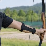 屋外の射場で前腕にアームガードを着けて弓を構える人