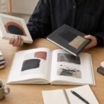 複数の美術書を机に広げて読み比べている様子