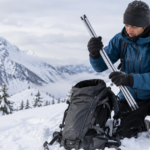 雪山でアバランチプローブをバックパックから取り出す登山者