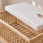 木製ベビーベッドの内側に白いマットレスを合わせるイメージ