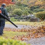 背負い式ブロワーで庭の落ち葉を吹き集める作業者