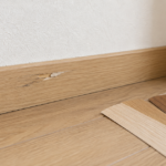 傷のある木目調の巾木と色の異なる補修シールの見本