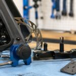 自転車のディスクブレーキ周辺と台座修正用工具を作業台に並べたイメージ