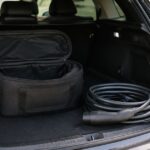 車の荷室に充電ケーブルと黒い収納バッグを並べた様子
