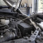 車のエンジンルームへエアブローガンで空気を吹き付ける様子