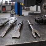 車の整備工場で形状の異なるエアハンマー用タガネを並べた様子