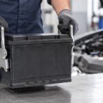 車用バッテリーをキャリアで持ち上げる整備士の手元