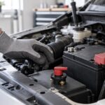 車のエンジンルームでバッテリーカットオフスイッチを検討している様子
