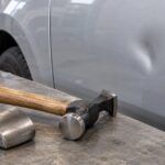 車のへこみの前にボディハンマーとドーリーを置いた作業場の写真