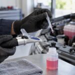 車のエンジンルーム脇で冷却水を濃度計に垂らしている様子
