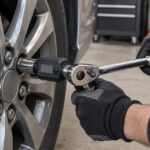 車のホイールに手動ラチェットとデジタルトルクアダプターを当てている様子