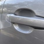 車のドアカップに透明な保護フィルムを当てている様子