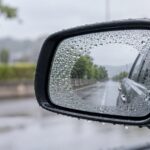 雨粒が付いた車のドアミラーと中央のクリアな鏡面部分