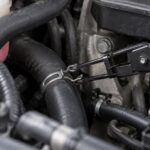 エンジンルーム奥のホースバンドをプライヤーでつかんでいる様子