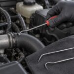 車のエンジンルームでホースピックを当てている様子
