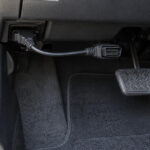 車の運転席足元でOBD2延長ケーブルを接続しているイメージ