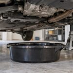 車体の下に黒いオイルドレンパンを置いたガレージの様子