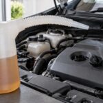 車のエンジンルーム脇にロングノズル付きオイルジョッキを置いた様子