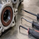 車のオイルシールと形状の異なる複数のプーラーを作業台に並べた様子