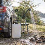 車のそばに置いた水タンクの簡易シャワーでサンダルを洗う様子
