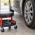 車のタイヤ横に工具トレー付きローリングシートを置いた整備風景