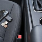 車のシートとセンターコンソールの隙間付近にスマホや鍵、小銭が置かれている様子
