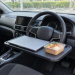 停車中の車内でハンドルテーブルにパソコンと弁当を置いた様子