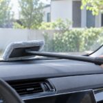 車内から長柄のモップでフロントガラス内側を拭いている様子